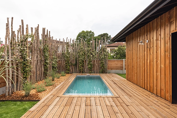 Photo immobilière d'une terrasse avec piscine et le jardin en arrière plan.